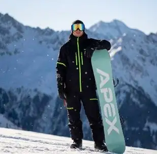Åkare står med en snowboard framför bergskedjan, framtagen med AI